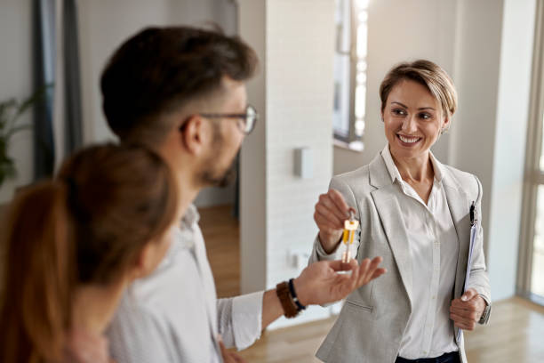 real state agent giving new house key to a young couple.